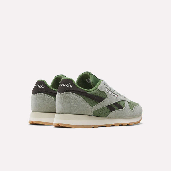 A pair of Reebok Men’s Classic Leather Shoes in green and light gray, featuring white EVA midsoles and gum outsoles, shown from a back side angle on a plain white background.