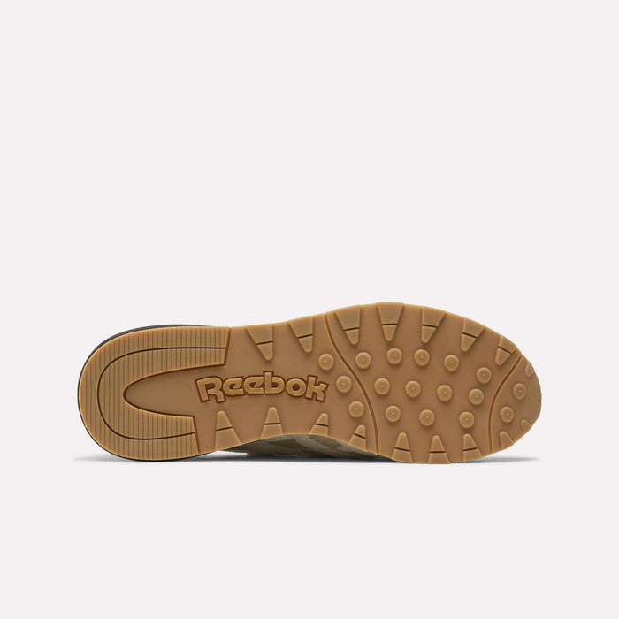 The image displays the bottom view of the Reebok Men's Classic Nylon 89 Shoes, highlighting a light brown rubber sole with circular grip patterns and an embossed Reebok logo, reminiscent of classic '80s sneaker designs.