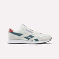 A pair of Reebok Men’s Classic Nylon Shoes in Chalk/Heritagered/Midnighttide is displayed in a side profile view against a plain white background. These mixed material sneakers showcase teal and red accents, blue side stripes, a white sole, and feature an EVA midsole for enhanced comfort.