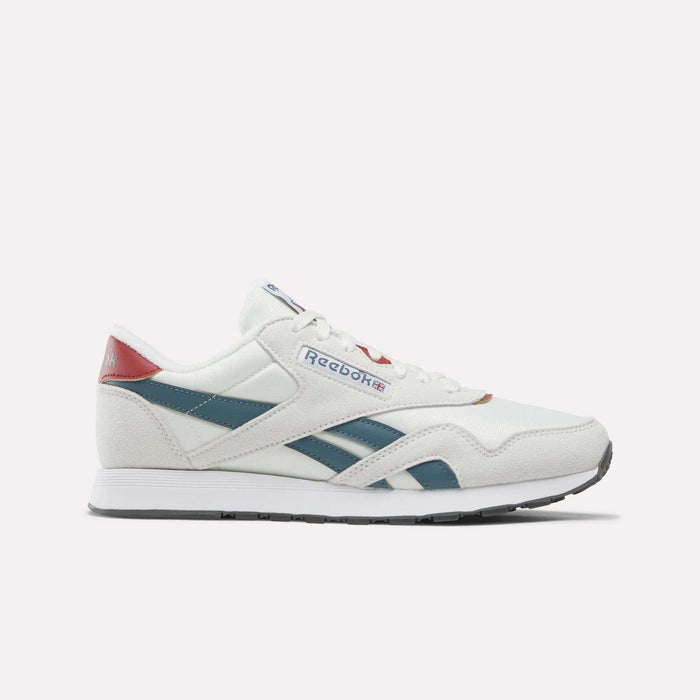 A pair of Reebok Men’s Classic Nylon Shoes in Chalk/Heritagered/Midnighttide is displayed in a side profile view against a plain white background. These mixed material sneakers showcase teal and red accents, blue side stripes, a white sole, and feature an EVA midsole for enhanced comfort.