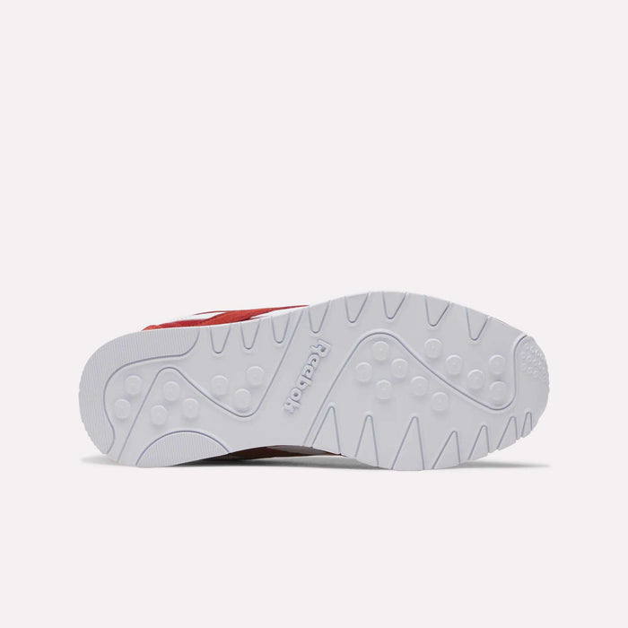 The image showcases the white outsole of the Reebok Men’s Classic Nylon Shoes, displaying circular and zigzag grip patterns along with the Reebok logo embossed at the center. Part of the red upper is visible, highlighting the enduring style of these retro sneakers for men.