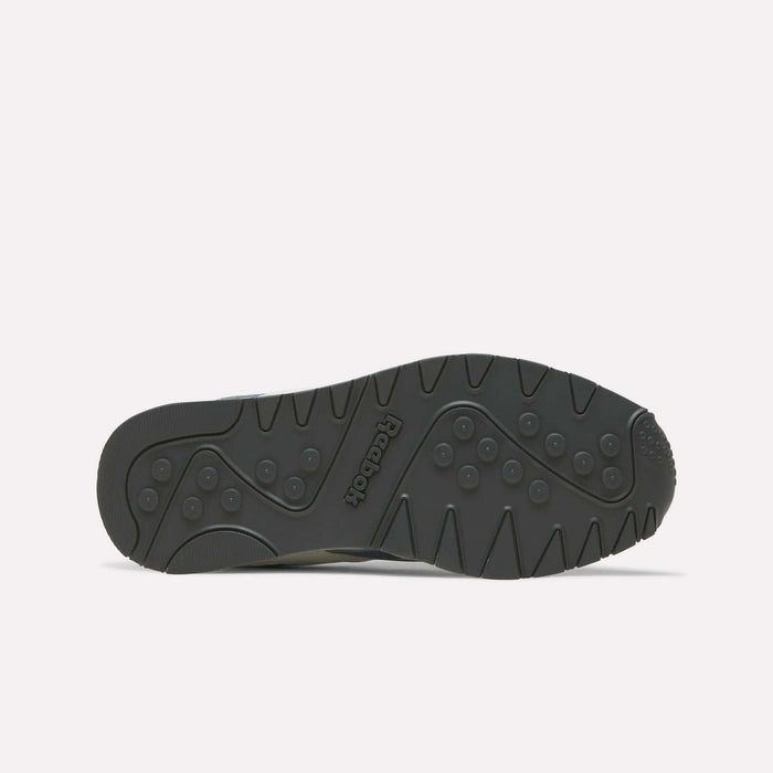 Black rubber outsole of the Reebok Men’s Classic Nylon Shoes, viewed from below, showcasing the Reebok logo, circular grip patterns, and wavy grooves for traction on a plain white background—emphasizing the durable construction of these mixed material sneakers and their signature EVA midsole cushioning.