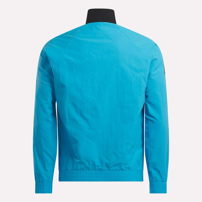 The back view shows the Men's Classics Track Top by Reebok in bright blue, with a black collar, elastic cuffs and hem, and lightweight fabric. The back has no visible logos or designs for a clean, casual look.