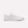 The Reebok Men's Club C 85 Shoes in Ftwr White/Chalk/Gold feature premium leather, a low-top silhouette, gold branding, white laces, and a slightly off-white sole, displayed on a plain white background.