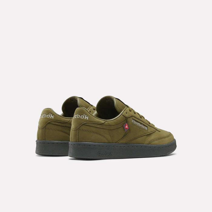 A pair of Reebok Men’s Club C 85 Shoes in olive green with black soles, displaying the Reebok logos on the sides and heels, presented against a plain white background.