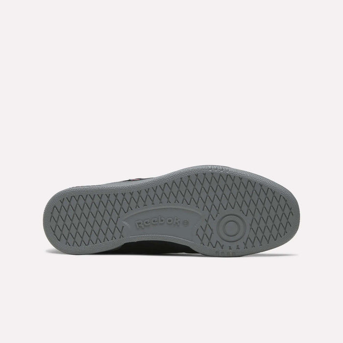 The underside of a Men’s Club C 85 Shoe by Reebok in gray, featuring a textured sole with a circular pattern, the Reebok logo, and a grid-like tread design.