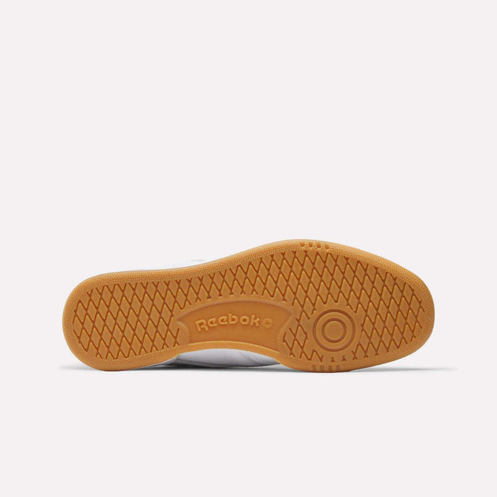 The image shows the bottom view of the Reebok Men's Club C 85 Shoes, featuring a light brown textured rubber sole with the Reebok logo and a circular design near the toe, set against a plain white background.