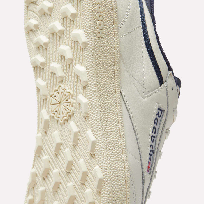 Close-up of the sole and side of the Reebok Men's Club C Golf Shoes, showcasing a spikeless outsole with hexagonal tread and Reebok logo—delivering classic golf style and comfort.