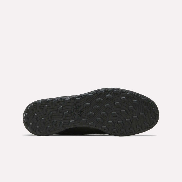 The Reebok Men's Club C Golf Shoes feature a black rubber spikeless outsole with textured, wavy treads and a central star design, ideal for golf, displayed on a plain white background.