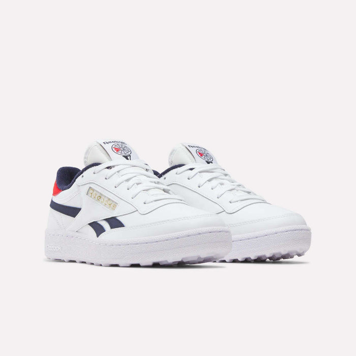 The Men's Club C Revenge Golf Shoes by Reebok are white with navy blue and red accents, feature the Reebok logo on the tongue and side, and have a spikeless outsole for traction, shown against a plain light background.