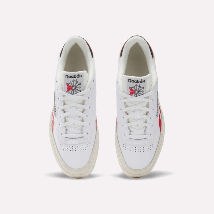 A pair of Men's Club C Revenge Shoes by Reebok in white leather, seen from above, featuring red and navy accents, perforated toes, and the classic Reebok logo with a starburst design on the tongue.