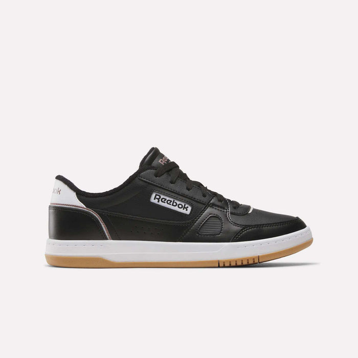 Introducing the Reebok Men’s Court LXS Shoes in Black/White/New Grey 1, expertly crafted from premium full grain leather. This stylish men’s court shoe features a classic white and gum sole, black laces, crisp white detailing around the heel, and a bold white Reebok logo on the side. Set against a plain white background for an elegant presentation.