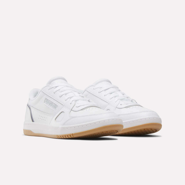Introducing the Men’s Court LXS Shoes by Reebok: These white low-top sneakers are crafted from premium full-grain leather and feature gum rubber soles, crisp white laces, and subtle silver accents. Shown against a plain light background, they offer a modern, elevated spin on classic men’s court footwear.