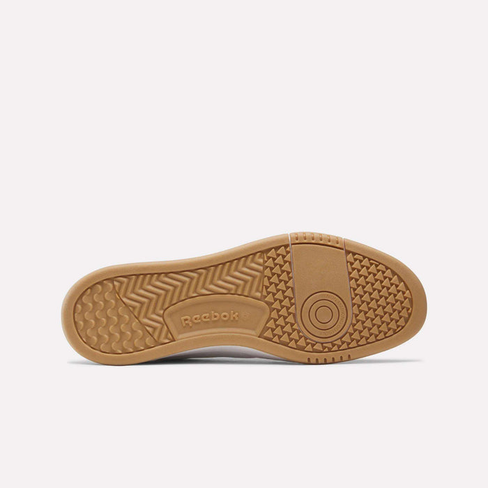 A single Men’s Court LXS Shoe by Reebok is shown from the bottom, highlighting its gum-colored sole with textured grip patterns and the Reebok logo at the center. Made from full grain leather, these court shoes offer a blend of classic style and durable performance.