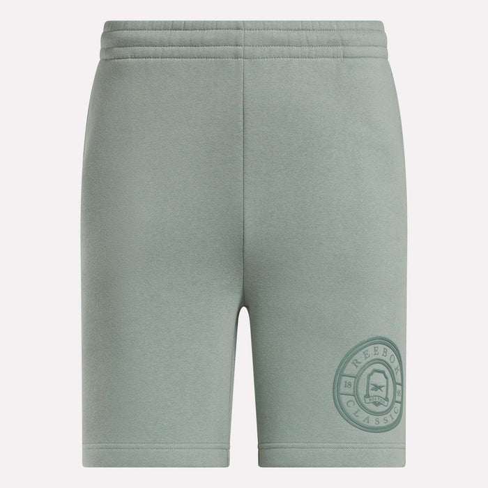 Light green Men's Crest Shorts by Reebok featuring a relaxed fit, elastic waistband, soft cotton fabric, and a darker green circular Reebok Classic logo near the left hem. Front view shown.