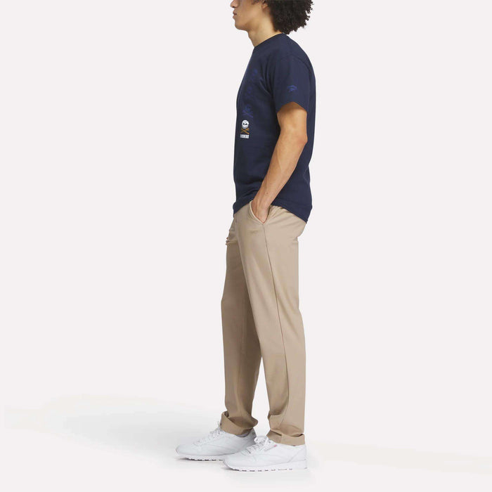 A man stands with his hands in his pockets, wearing the Reebok Men's Crushers Icon Tee.