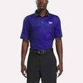 A man wearing a Reebok Men's Crushers Polo Shirt in Vector Navy and Trophy Gold, featuring a dark blue design, stands with his arms relaxed at his sides against a plain background.
