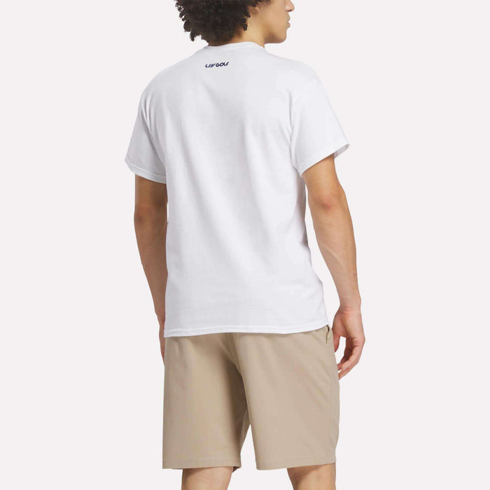 A person stands with their back to the camera, wearing a white Reebok Men's Crushers Tee and beige shorts. The shirt features a small UFO OUT logo near the neckline on the back.