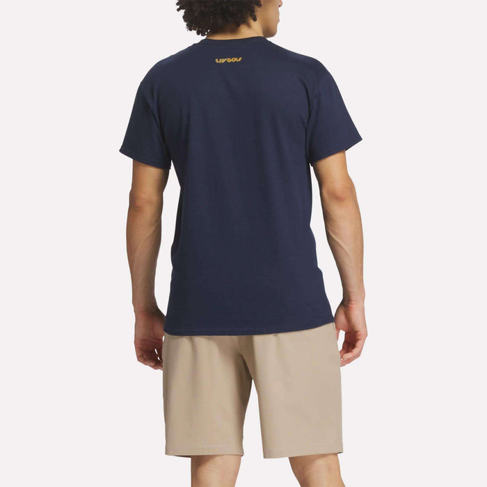 A man faces away from the camera wearing a Reebok Men's Crushers Tee in navy and beige shorts against a plain white background.