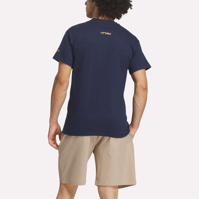A person faces away against a plain white background, wearing the Reebok Men's Crushers Wordmark Tee in navy blue with yellow text near the collar, paired with tan shorts.