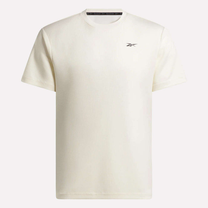 The Reebok Men's Director Short Sleeve Top is displayed on a flat background. This off-white training tee features a small Reebok logo on the left chest and offers a stretchy, comfortable fit for ease of movement.