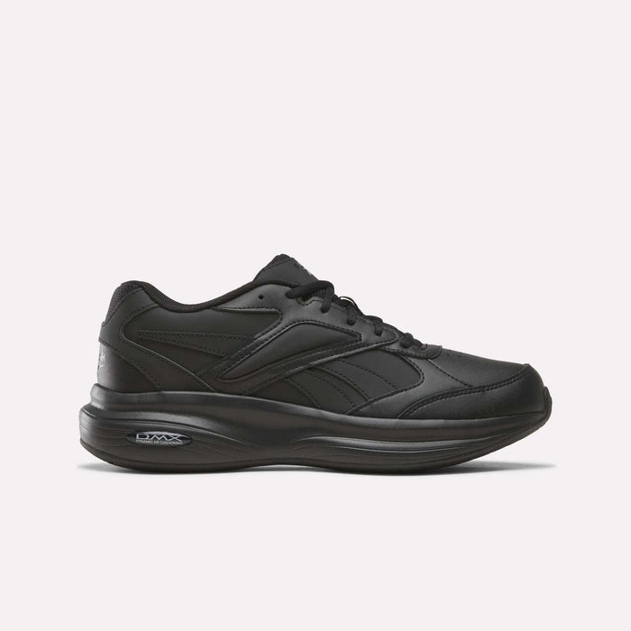A men’s walking shoe from Reebok, the DMX Comfort+ Walk Ultra, in an all-black colorway (Aha - Black/Black/Black), featuring a low-top athletic design, lace-up closure, and a thick cushioned sole enhanced with DMX Comfort+ cushioning. The shoe is displayed against a plain, light-colored background to highlight its sleek appearance.