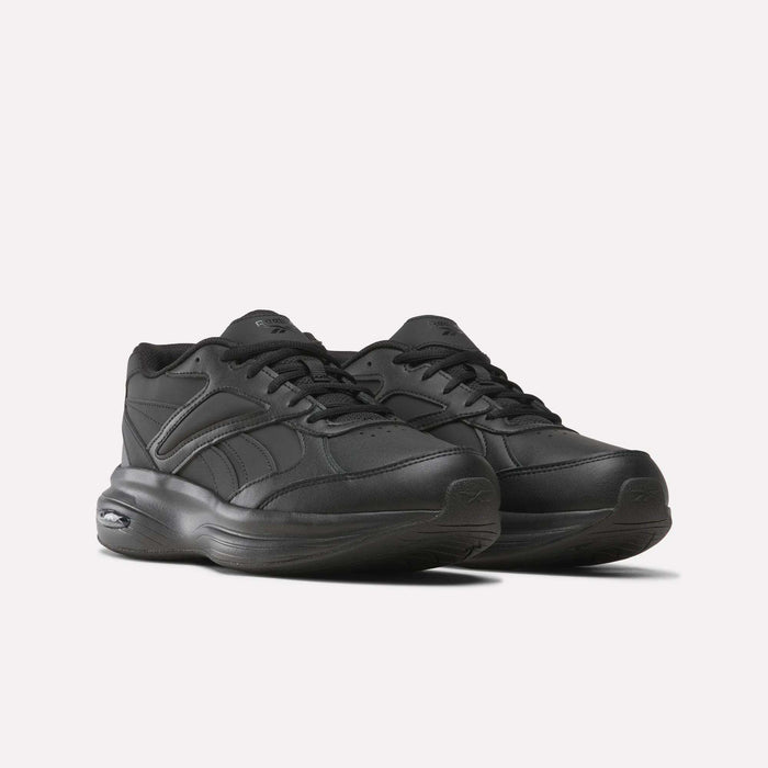 A pair of black Reebok Men’s DMX Comfort+ Walk Ultra Shoes with thick soles, lace-up fronts, and subtle stitched detailing are displayed against a plain white background. These athletic sneakers feature DMX Comfort+ cushioning for enhanced support and all-day comfort.