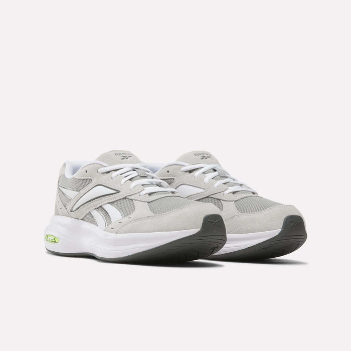 A pair of Reebok Men’s DMX Comfort+ Walk Ultra Shoes in light gray and white, featuring white laces, a chunky white sole with black accents on the outsole, and a small green detail near the heel. These athletic sneakers are designed with Reebok’s DMX Comfort+ technology for superior cushioning, and are displayed on a plain white background.