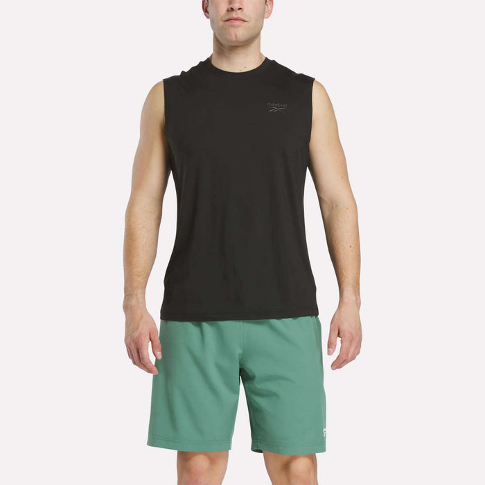 A man in a Reebok Men's Elite Sleeveless Top and green shorts stands facing forward against a plain white background.