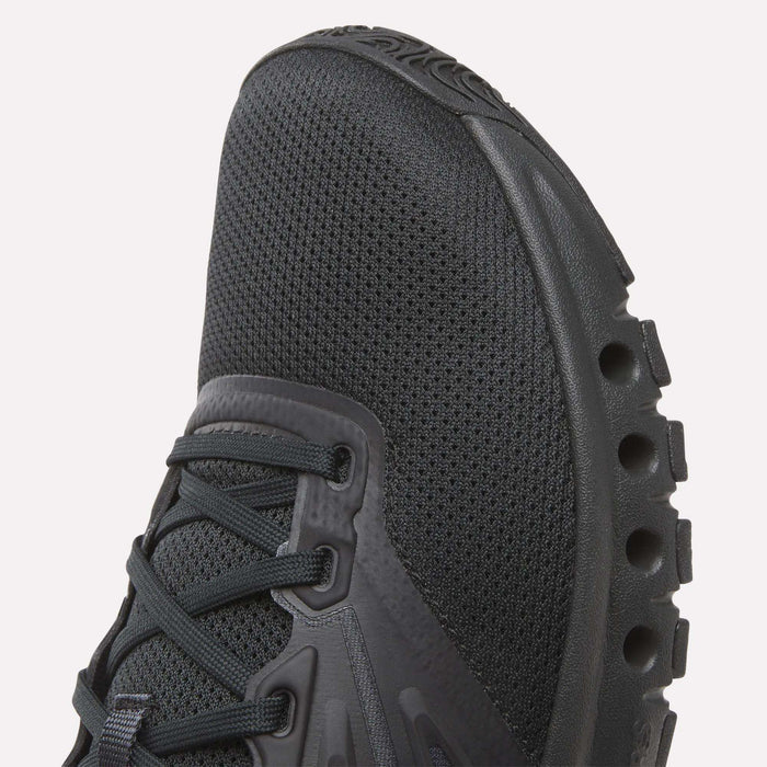 Close-up of the toe and side of Reebok Men's ERS Training Shoes, featuring a textured mesh upper, synthetic overlays, and a distinctive midsole with circular cutouts for premium cushioning.