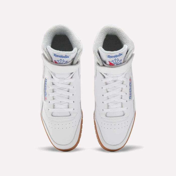 A pair of Men’s EX-O-FIT Hi Shoes by Reebok in white leather, with gray inner lining, blue and red logos on the tongue and side, and brown rubber soles, shown from above against a light background.