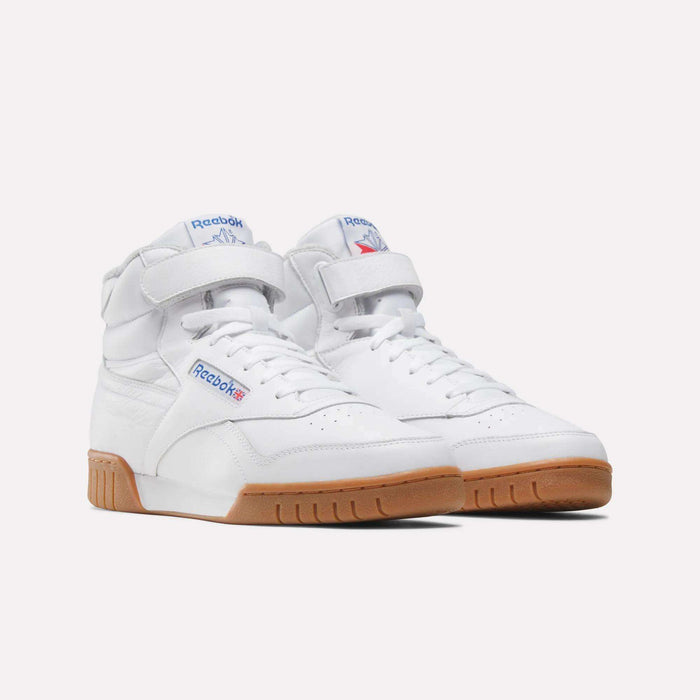 The Men's EX-O-FIT Hi Shoes by Reebok feature white leather, Velcro ankle straps, blue and red logos, perforated toe boxes, and gum rubber soles for a retro high-top style—shown against a light background.