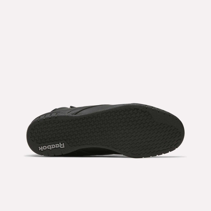 The image displays the black rubber sole of a Reebok Men's EX-O-FIT Hi Shoe, seen from beneath. It showcases a herringbone tread pattern and the Reebok logo near the heel, highlighting its retro-inspired design.