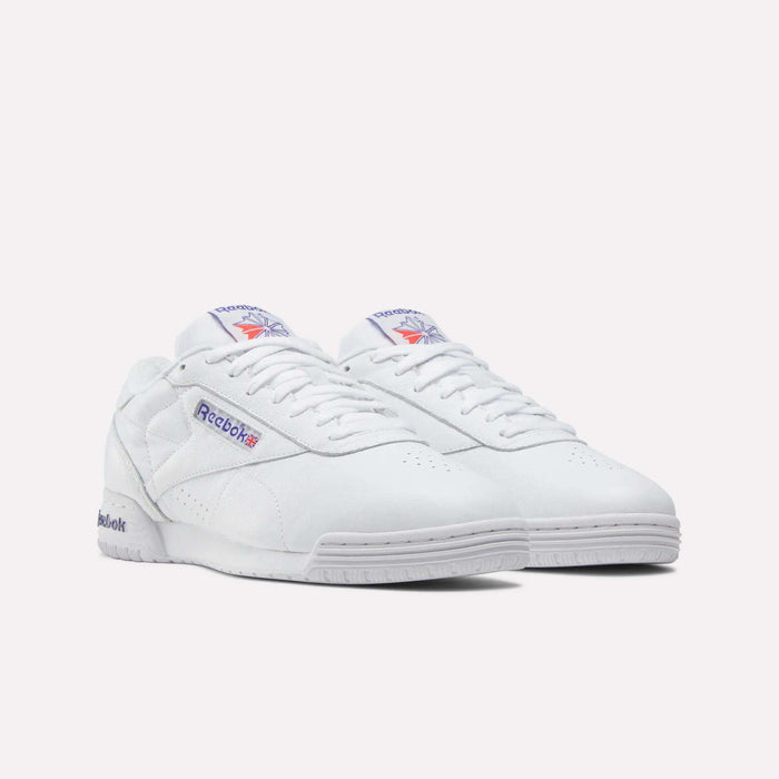The Men's Exofit Lo Shoes by Reebok are white low-profile sneakers featuring purple and red Reebok logos on the side and tongue, shown against a plain white background.