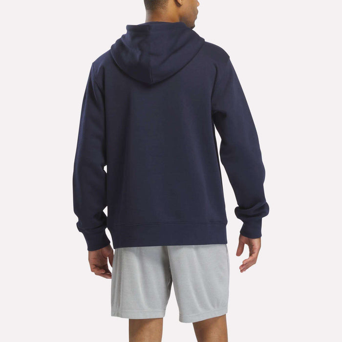 A person is standing and facing away from the camera against a plain background, wearing the Reebok Men's Finisher Hoodie in navy along with light gray shorts.