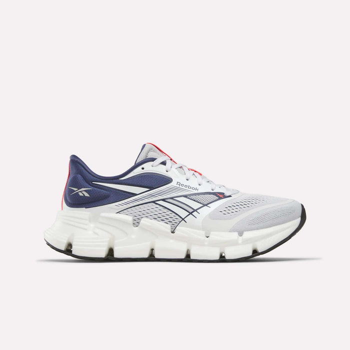 The Reebok Men's FloatZig 2 Running Shoes feature a white and navy mesh upper, Superfloat+ cushioning, thick segmented white sole, navy and black accents, and Reebok logos on the heel and side.