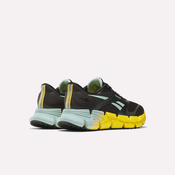 The Reebok Men's FloatZig 2 Running Shoes in black with light blue accents and bold yellow soles, featuring Superfloat+ cushioning, are shown from the back and side angles on a white background.