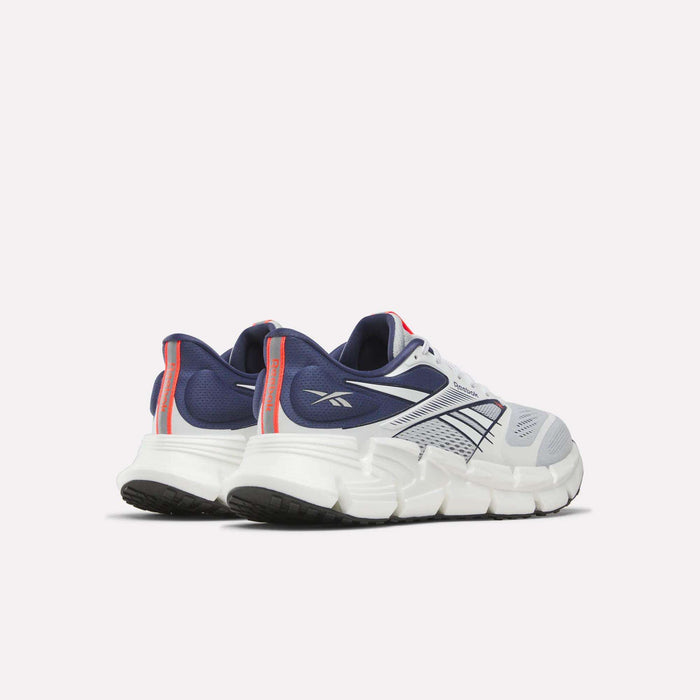 The Reebok Men's FloatZig 2 Running Shoes in white and navy, with red accents, are shown from a rear side view and feature chunky soles, mesh uppers, and Superfloat+ cushioning for added comfort.