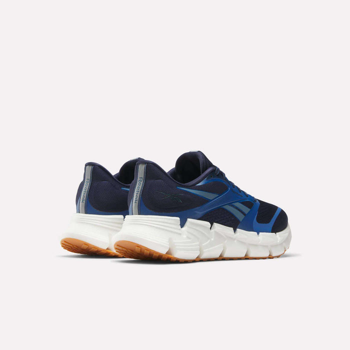 The Reebok Men's FloatZig 2 Running Shoes in navy blue with blue accents, white Superfloat+ cushioned chunky soles, and tan outsoles are shown from the back and slightly to the side against a plain light background.