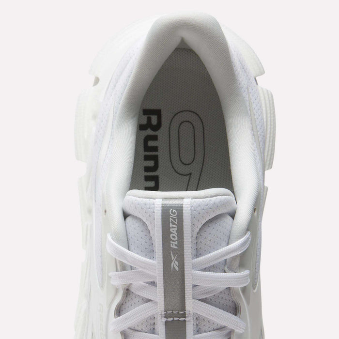 Top view of a white Reebok Men's FloatZig 2 Running Shoe with white laces. "Runner 9" is on the insole, and "FLOATZIG" plus logo appear on the tongue, emphasizing energy-return cushioning for superior comfort.