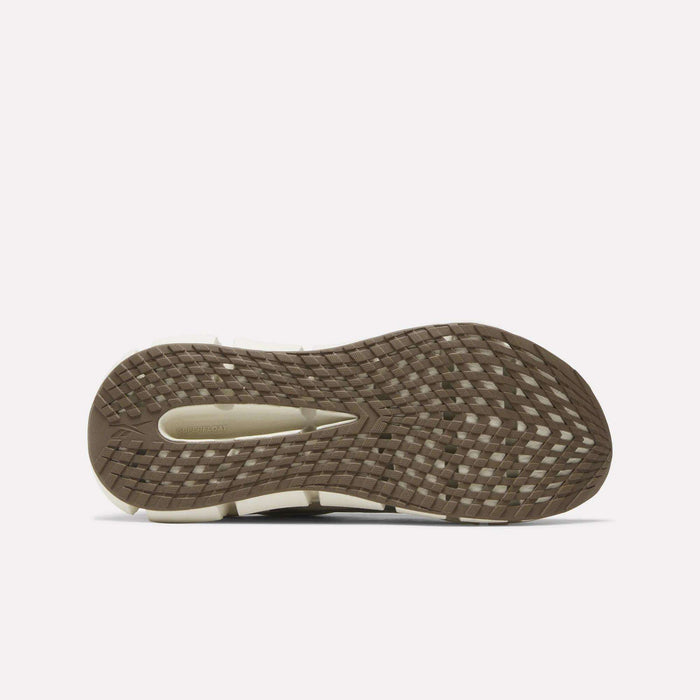 Bottom view of Reebok Men's FloatZig 2 Running Shoes, featuring a textured brown rubber sole with grid-like tread, beige arch inset, and Superfloat+ cushioning. Displayed against a plain white background.