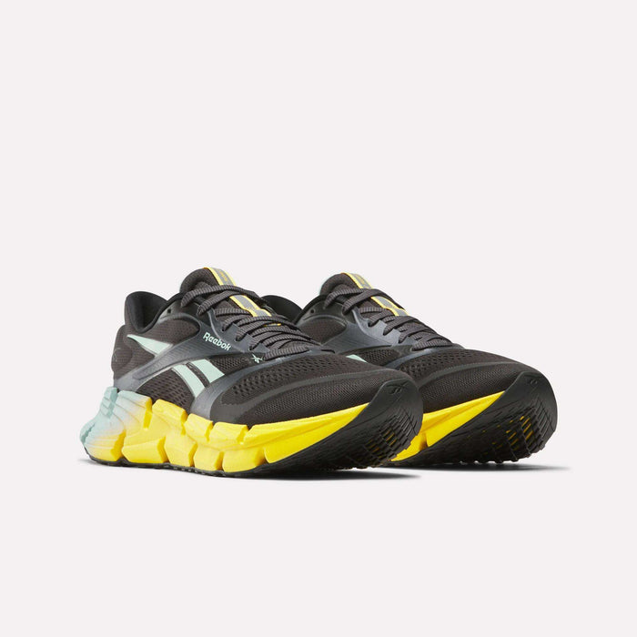 A pair of Reebok Men's FloatZig 2 running shoes in black with light blue side stripes and thick yellow-black soles, featuring Superfloat+ cushioning, displayed against a plain white background.