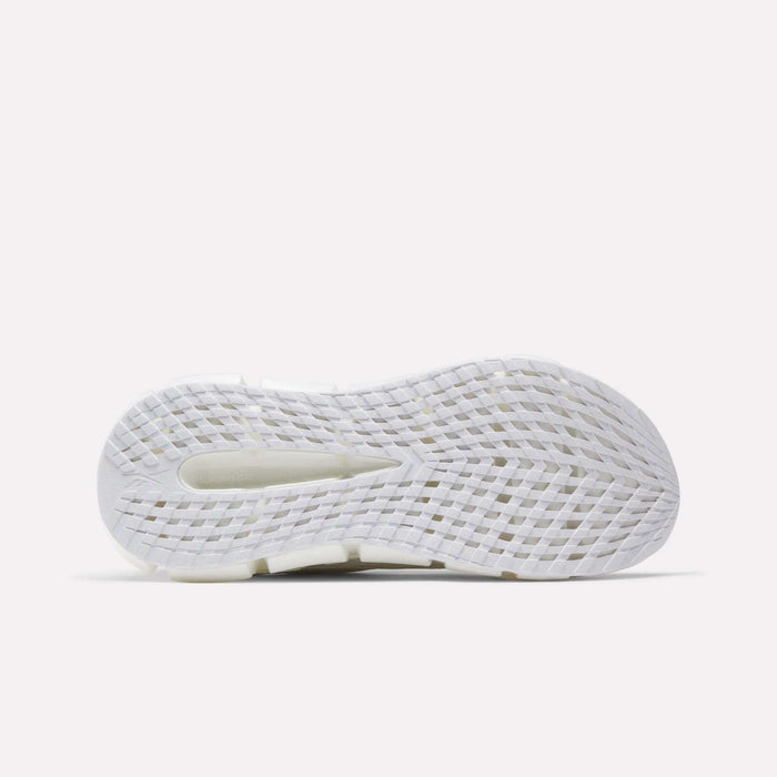 The image shows the bottom view of a white Reebok Men's FloatZig 2 Running Shoe sole with grid-like textured grooves, a central cutout for traction and flexibility, and energy-returning cushioning on a light gray background.