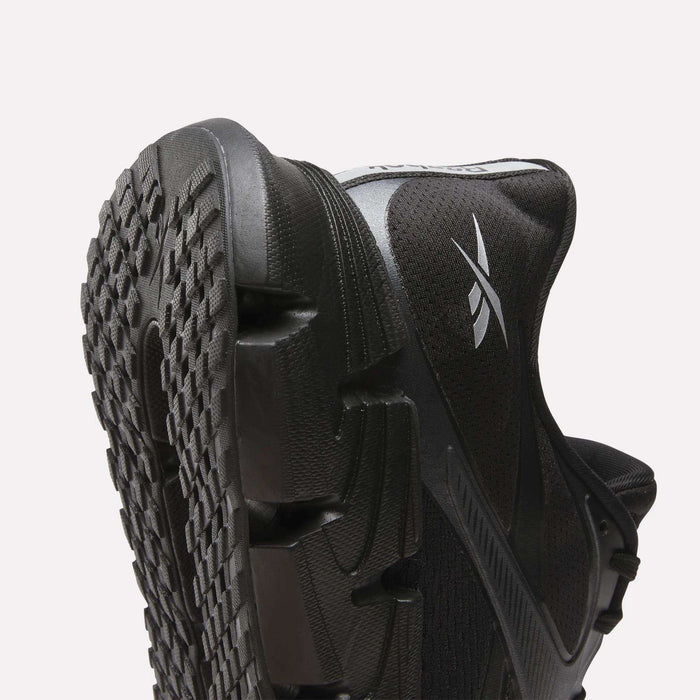 Close-up of Reebok Men's FloatZig 2 Running Shoes in black, featuring a textured rubber sole, energy-returning cushioning, and a white Reebok logo on the side, set against a plain light background.