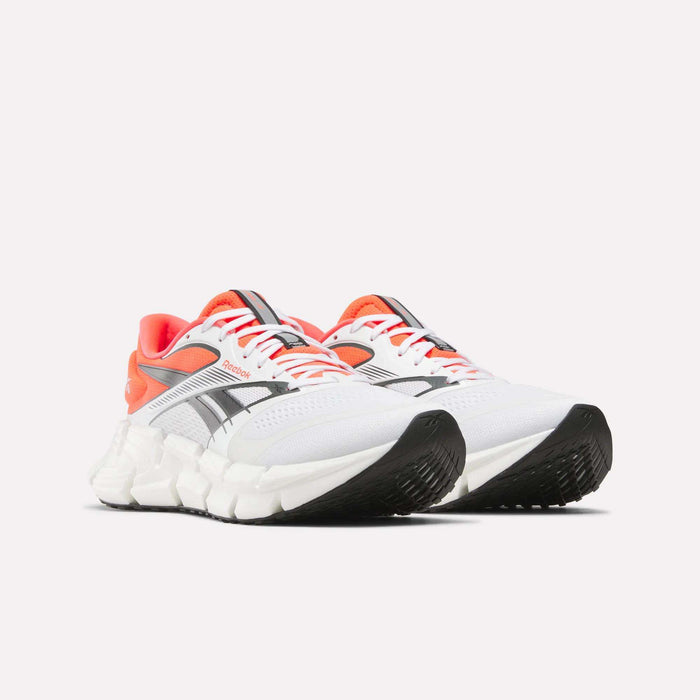 A pair of Reebok Men's FloatZig 2 Running Shoes in white with black and gray accents, orange lining, and chunky white soles with Superfloat+ cushioning, displayed side by side on a plain white background.