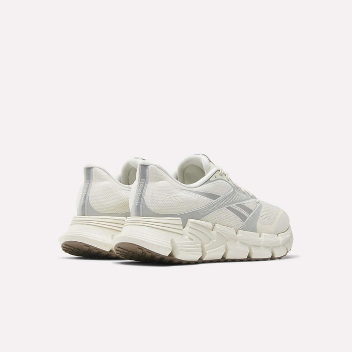 A pair of Reebok Men's FloatZig 2 running shoes in off-white with chunky, textured soles, Superfloat+ cushioning, and light gray accents, shown from the back-left on a plain white background.
