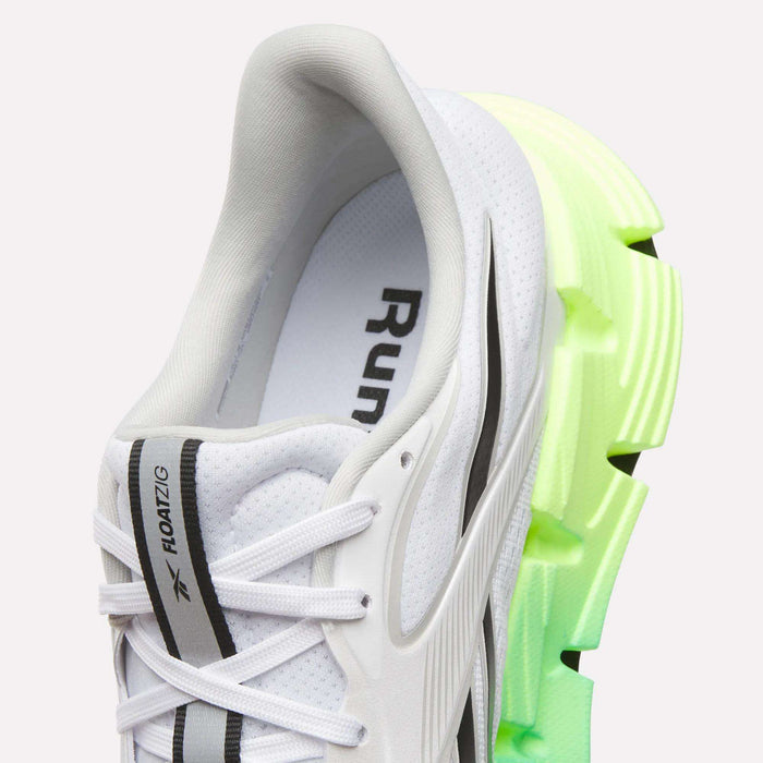 Close-up of the Reebok Men's FloatZig 2 Running Shoes in white with black and gray accents, white laces, and a thick sole fading to neon yellow-green at the heel—showcasing responsive Superfloat+ cushioning.