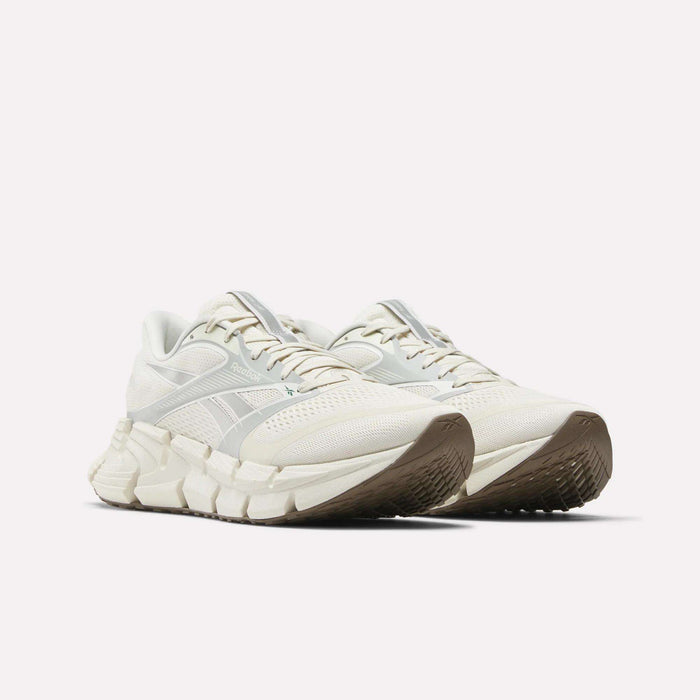 The Men's FloatZig 2 Running Shoes by Reebok feature an off-white design with chunky, textured soles, brown outsoles, and Superfloat+ cushioning, shown against a plain white background.