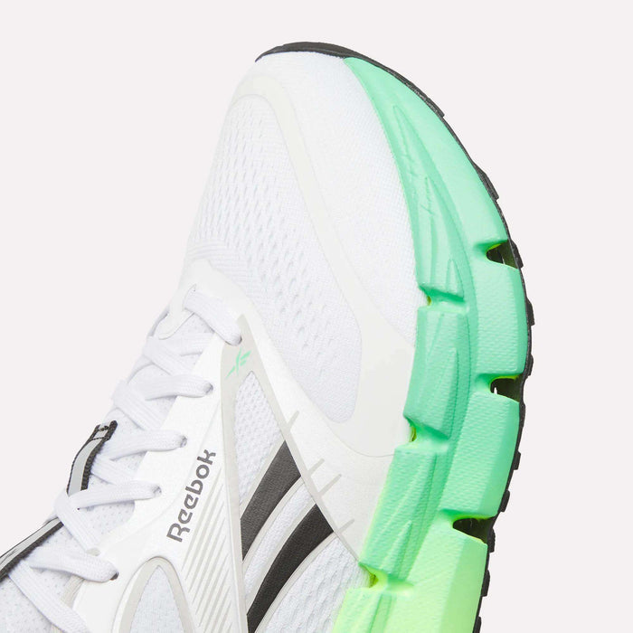 A close-up of the Reebok Men's FloatZig 2 Running Shoes in white with black accents and a chunky sole fading from light green to dark green at the front, featuring Superfloat+ cushioning, angled to display the side and part of the sole.