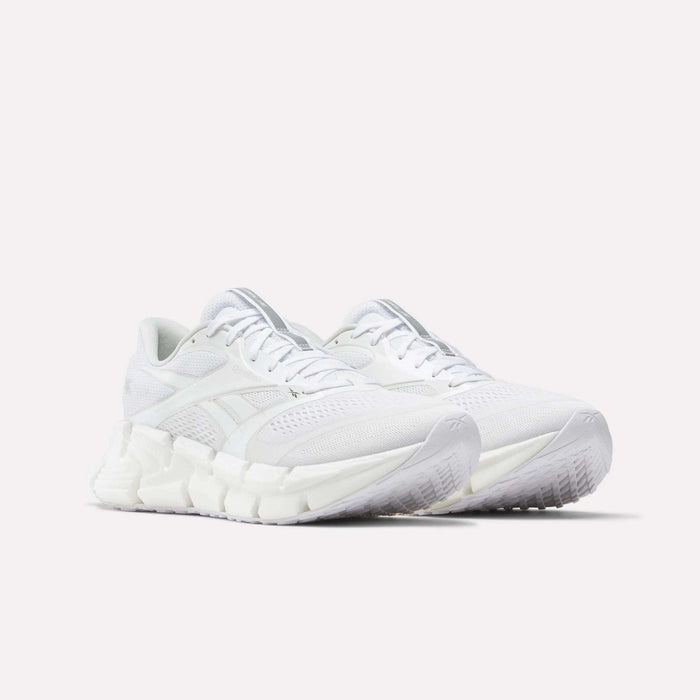 A pair of Reebok Men's FloatZig 2 Running Shoes in white, featuring mesh uppers, energy-returning cushioning, and textured soles, are displayed side by side at a slight angle on a plain light background.